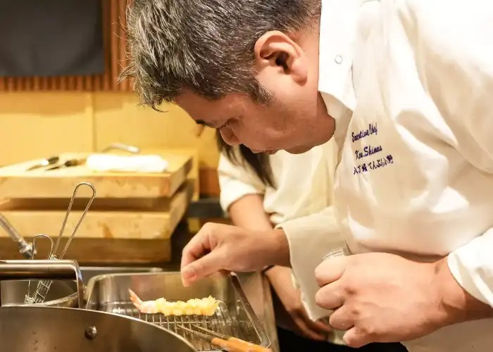 Chef Shimura Koichiro sprinkling salt onto a crispy ebi tempura.
